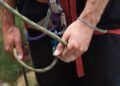 Hands gripping a climbing rope with a carabiner and harness, illustrating Mastering Website Updates: Essential Tips for Effortless Management through steady control and safety.