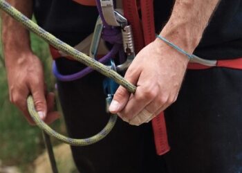 Hands gripping a climbing rope with a carabiner and harness, illustrating Mastering Website Updates: Essential Tips for Effortless Management through steady control and safety.