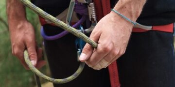 Hands gripping a climbing rope with a carabiner and harness, illustrating Mastering Website Updates: Essential Tips for Effortless Management through steady control and safety.