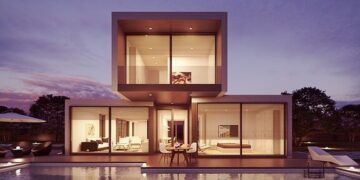 Contemporary two-story glass house at twilight with pool reflections, illustrating stability to Unlock Your Website’s Potential with Regular Maintenance