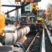Construction crew in high-visibility gear installing a large pipeline along railway tracks, illustrating the need to Avoid These 3 Website Maintenance Mistakes to Boost Performance.