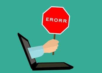 A hand reaches from a laptop holding a red stop sign reading ERORR as a visual reminder to Avoid These Common Website Backup Mistakes That Could Cost You Big.