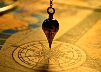 A vintage pendulum over a compass on an old map symbolizes Master the Art of Scheduling Website Backups for Ultimate Security.