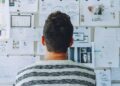 Person standing in front of a wall of pinned website sketches and notes to Boost Your Small Business Success with a Website Maintenance Plan.