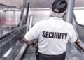 Uniformed security guard on an escalator with SECURITY printed on the shirt illustrating Neglecting Website Security Updates: The Risks You Can’t Afford