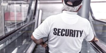 Uniformed security guard on an escalator with SECURITY printed on the shirt illustrating Neglecting Website Security Updates: The Risks You Can’t Afford