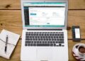 MacBook Air displaying a website admin dashboard on a wooden desk next to a smartphone, notebook, and coffee — Uncover the Best Tools for Website Uptime Monitoring Today!